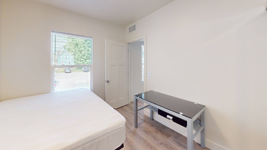 A bedroom with a bed, a table, and a window.